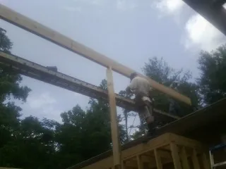Carpenter setting a ridge beam over a new addition frame — Ice Dam Removal by Roofing Brothers in Smiley