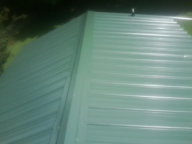 New green metal panels meeting at the ridge of a roof — Flat Roof Repair work by our crew in Smiley