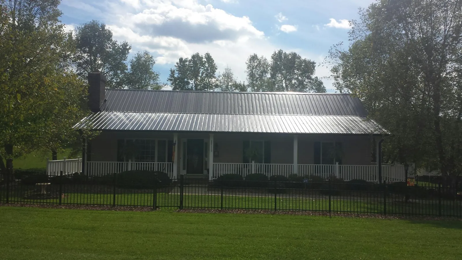 Gray metal roof on a brick ranch with a full width front porch — Gutter Guard Installation work by our crew in Smiley